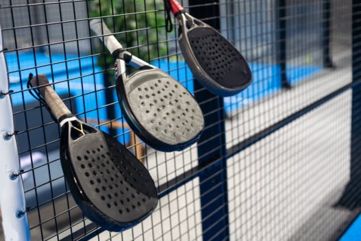 3 padelbat der sidder i gitteret på en padelbane